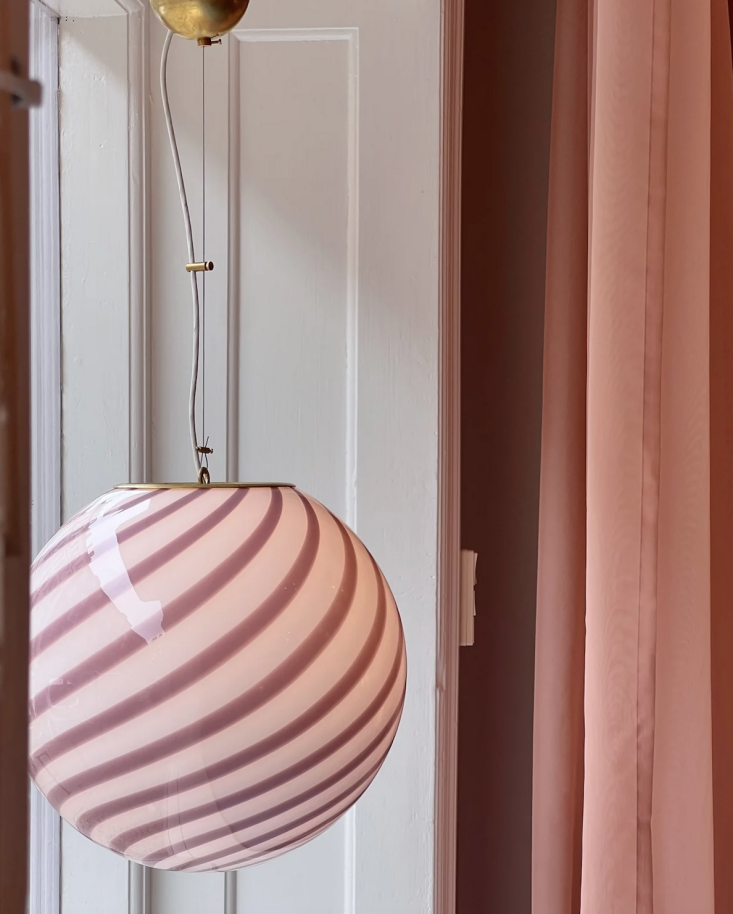 A handblown Murano glass pendant light with pink and lavender stripes.