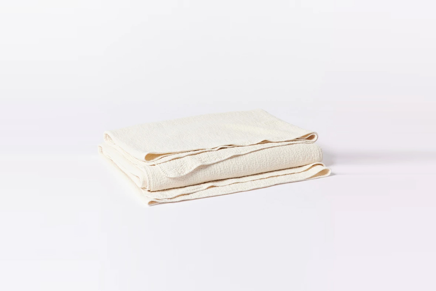 An undyed organic matelasse blanket with a subtle pebbled texture.