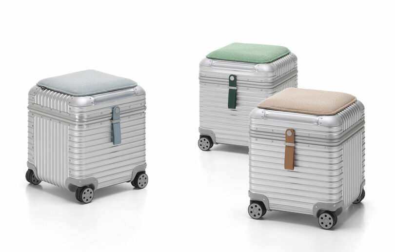 Three silver aluminum stools with grooved surfaces and cushioned tops in Ice Blue, Emerald, and Papyrus.
