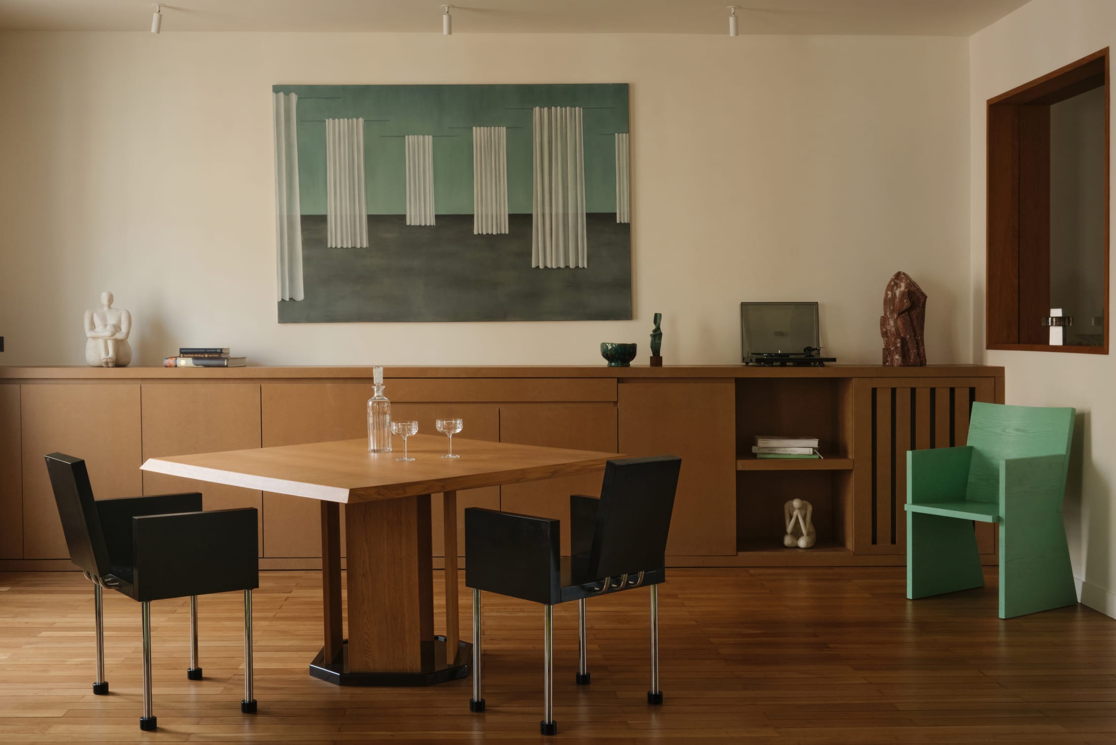 Wide shot of a light-filled living room featuring warm wood walls and curated art.