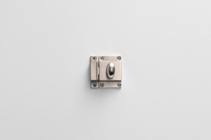 A close-up of a satin nickel cabinet latch on a gray kitchen cupboard.