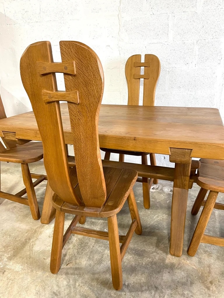 A midcentury oak dining table with matching chairs featuring thick, rounded wooden frames.