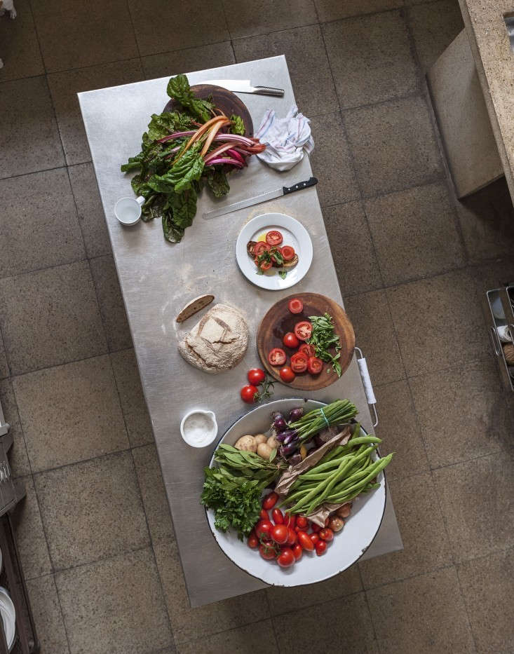 A modern kitchen featuring a stainless steel worktop on an old school table base.