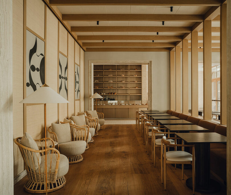 A minimalist hotel lounge with rattan chairs, abstract wall art, and open shelving with pottery.