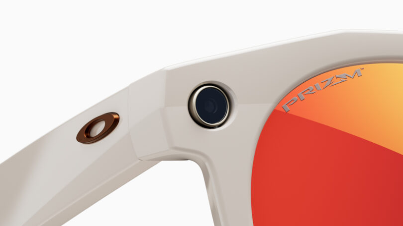 Close-up of beige smart glasses with a small integrated camera on the frame.