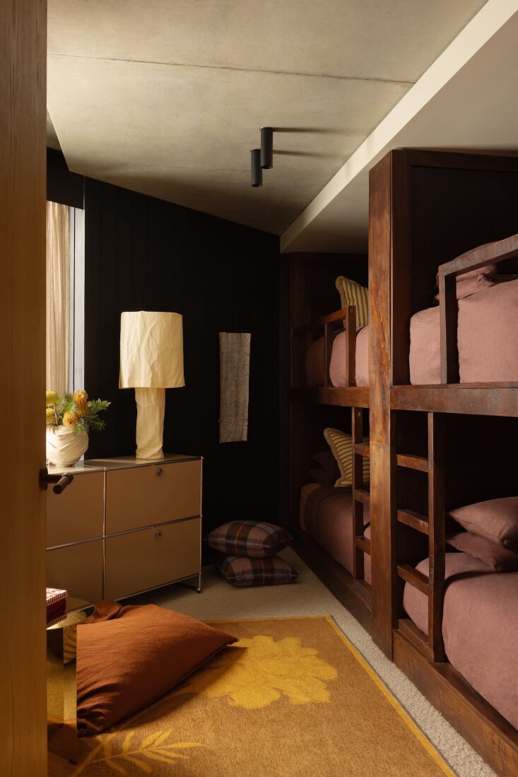 A custom-built wooden bunk room with deep beds and integrated shelving in a triangular space.
