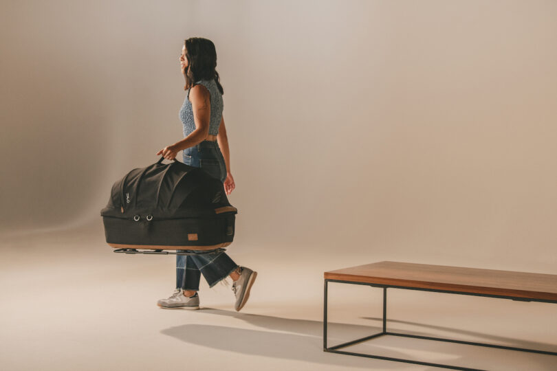 A woman carrying the Tavo Maeve carrier by its vegan leather handle.