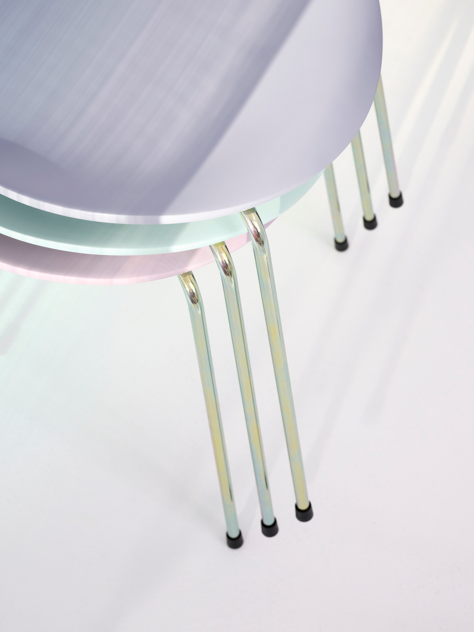 Macro detail of the iridescent zinc chrome base of a Series 7 chair reflecting multiple colors.