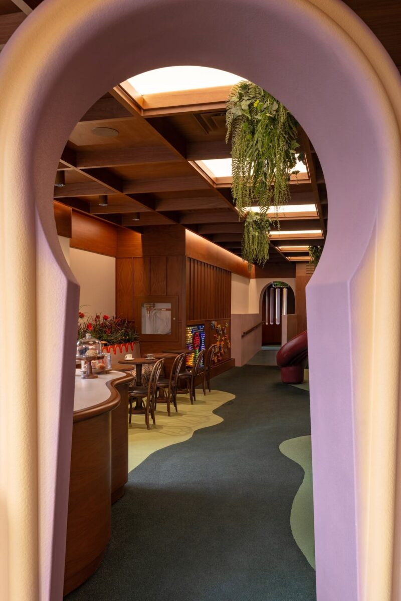 View through a keyhole-shaped wooden doorway into a green-carpeted play area.