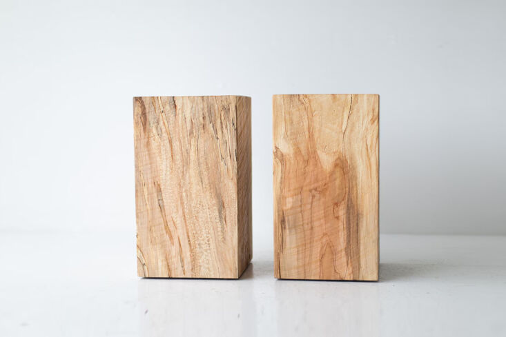 Pared-back solid timber nightstands placed next to a bed in a minimalist room.