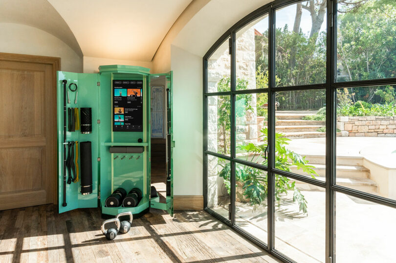 A compact Ottagono fitness cabinet positioned near a large window in a modern home.