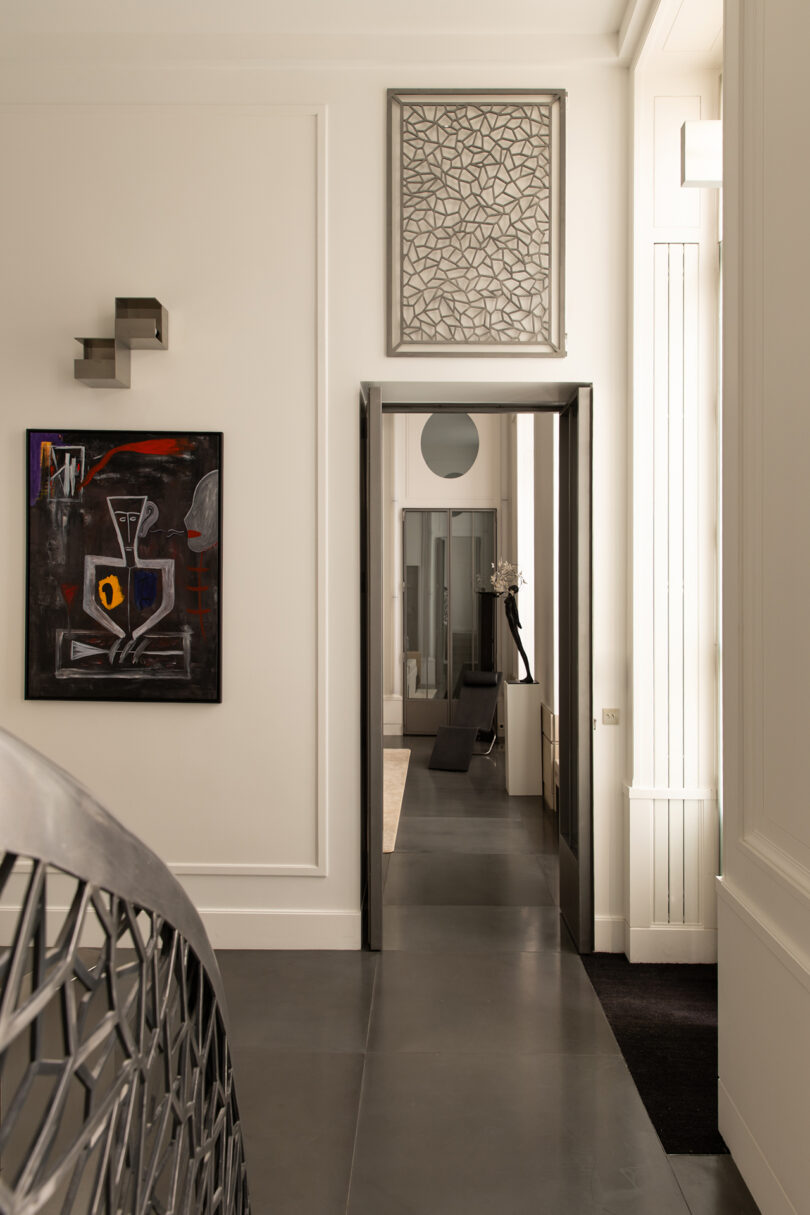 A sleek hallway decorated with geometric artwork and abstract paintings in a luxury apartment.