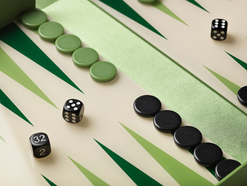 Close-up of a green and cream backgammon board with dice and checkers.