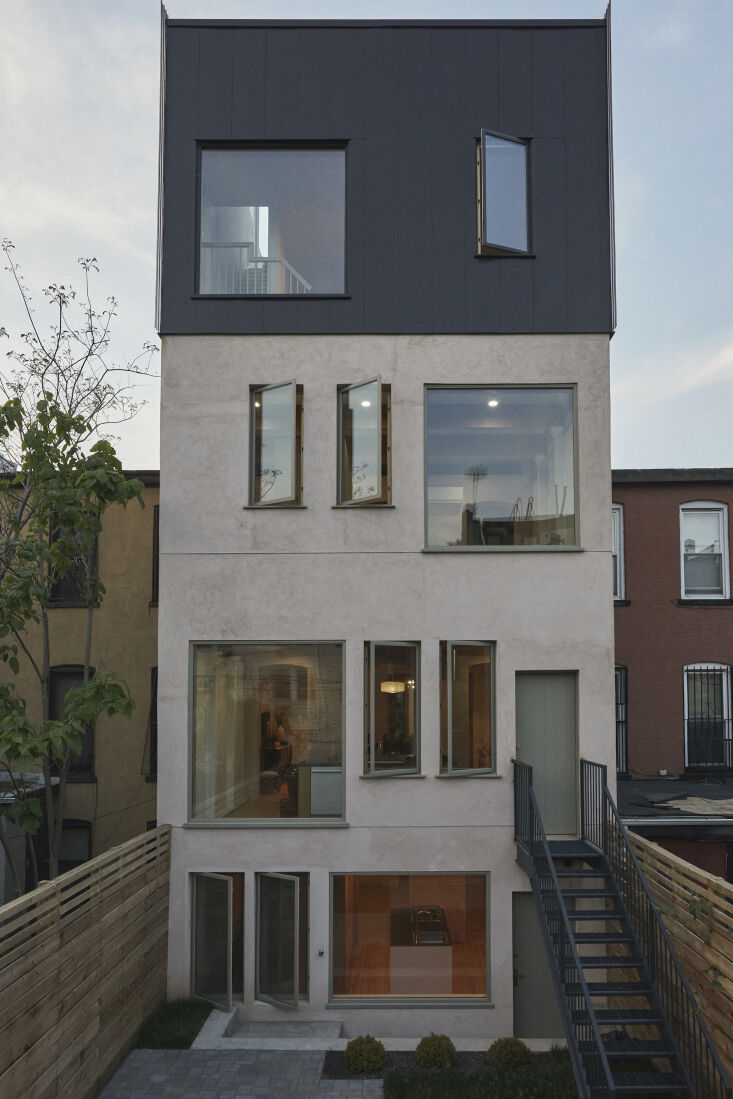 Rear view of a Brooklyn townhouse featuring a concrete extension and a third floor clad in Corten steel.