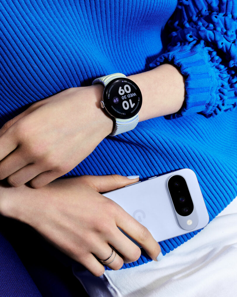 A person wearing a smartwatch resting their hand on a modern smartphone.