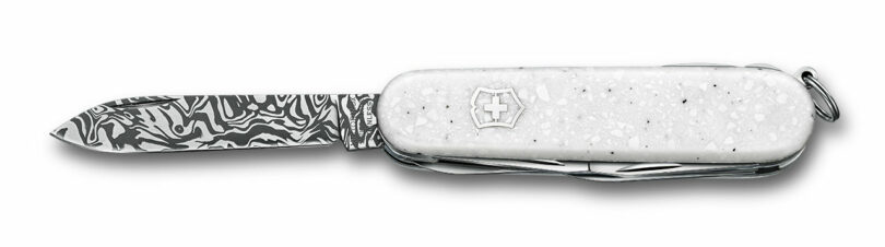 A Victorinox Swiss Army knife with its Svavner pattern Damasteel blade extended against a white background.