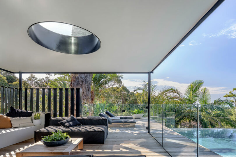High-end outdoor patio featuring a unique circular skylight in the roof structure and glass safety railings.