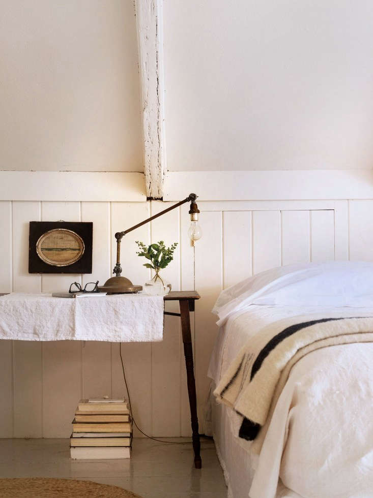 A woman relaxing on a bed dressed in white Sferra linens.