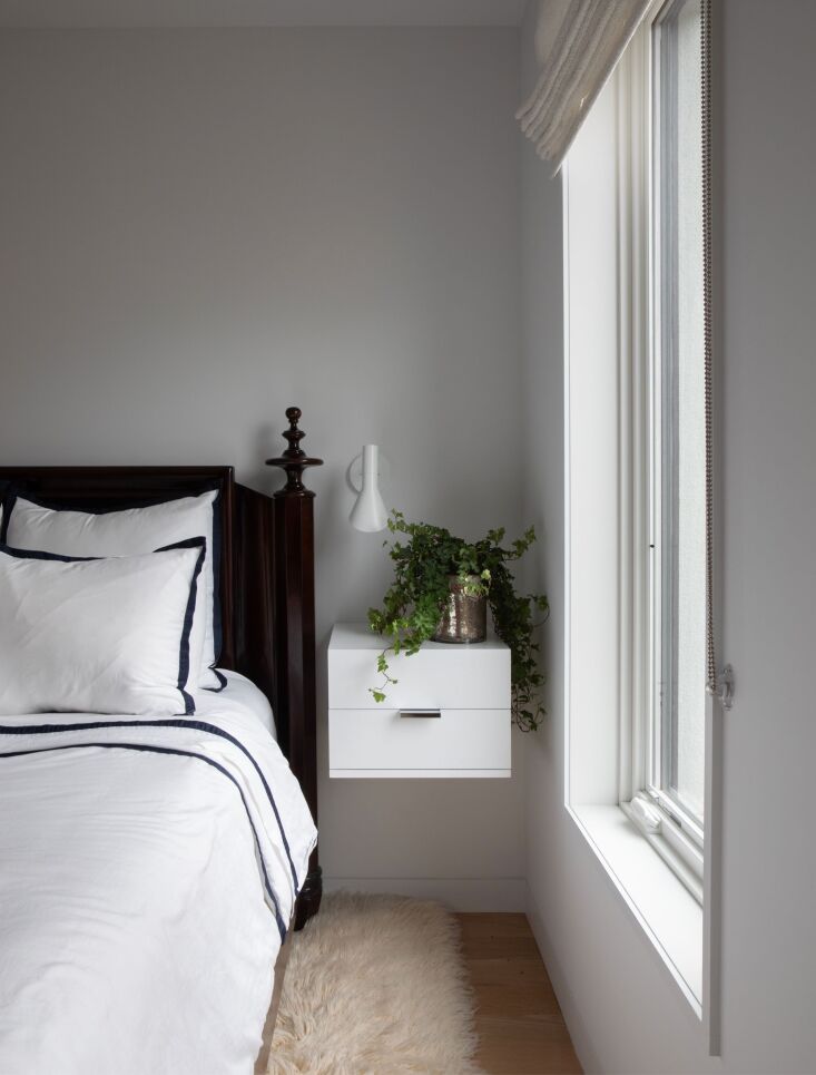 A bedroom interior showing a wall-mounted nightstand and an Arne Jacobsen sconce.