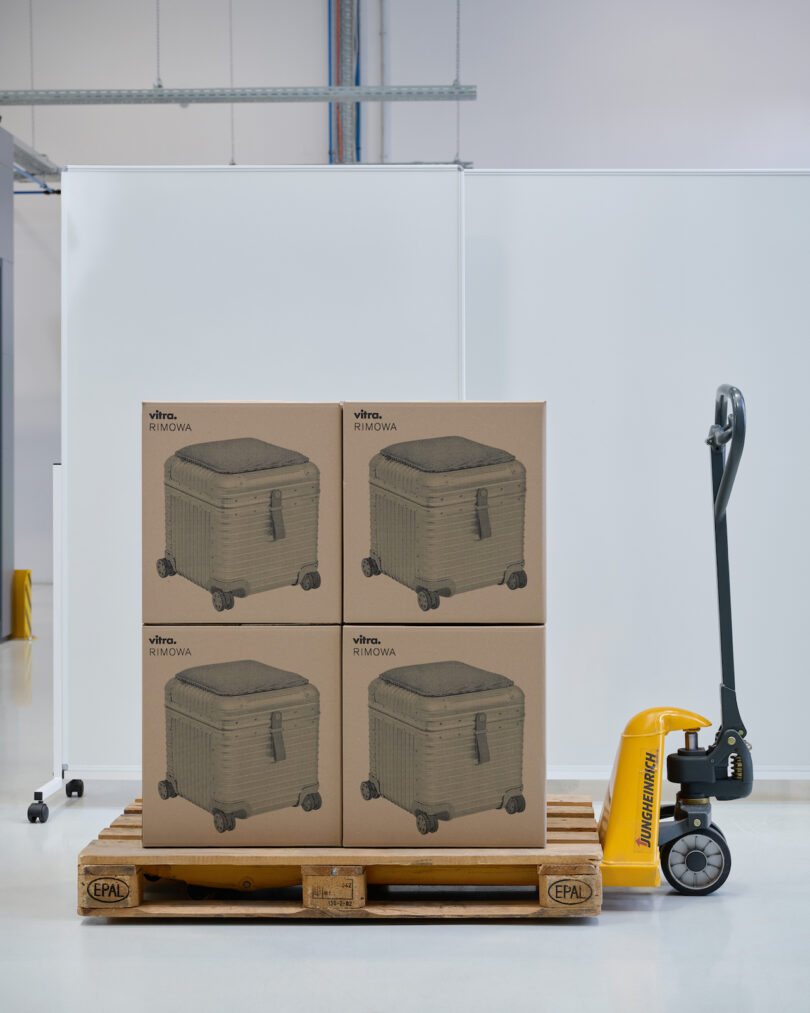 Stack of cardboard boxes featuring illustrations of the collaboration pieces on a wooden pallet in a warehouse.