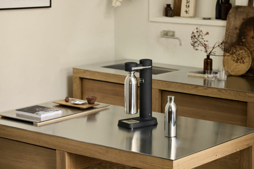 An Aarke To-Go Bottle and a Carbonator 3 on a minimalist kitchen countertop.