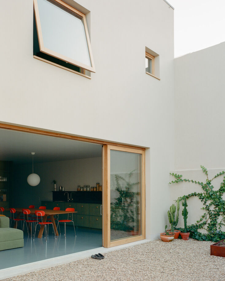 Modernist extension of a Lisbon house with large doors opening to a gravel courtyard.