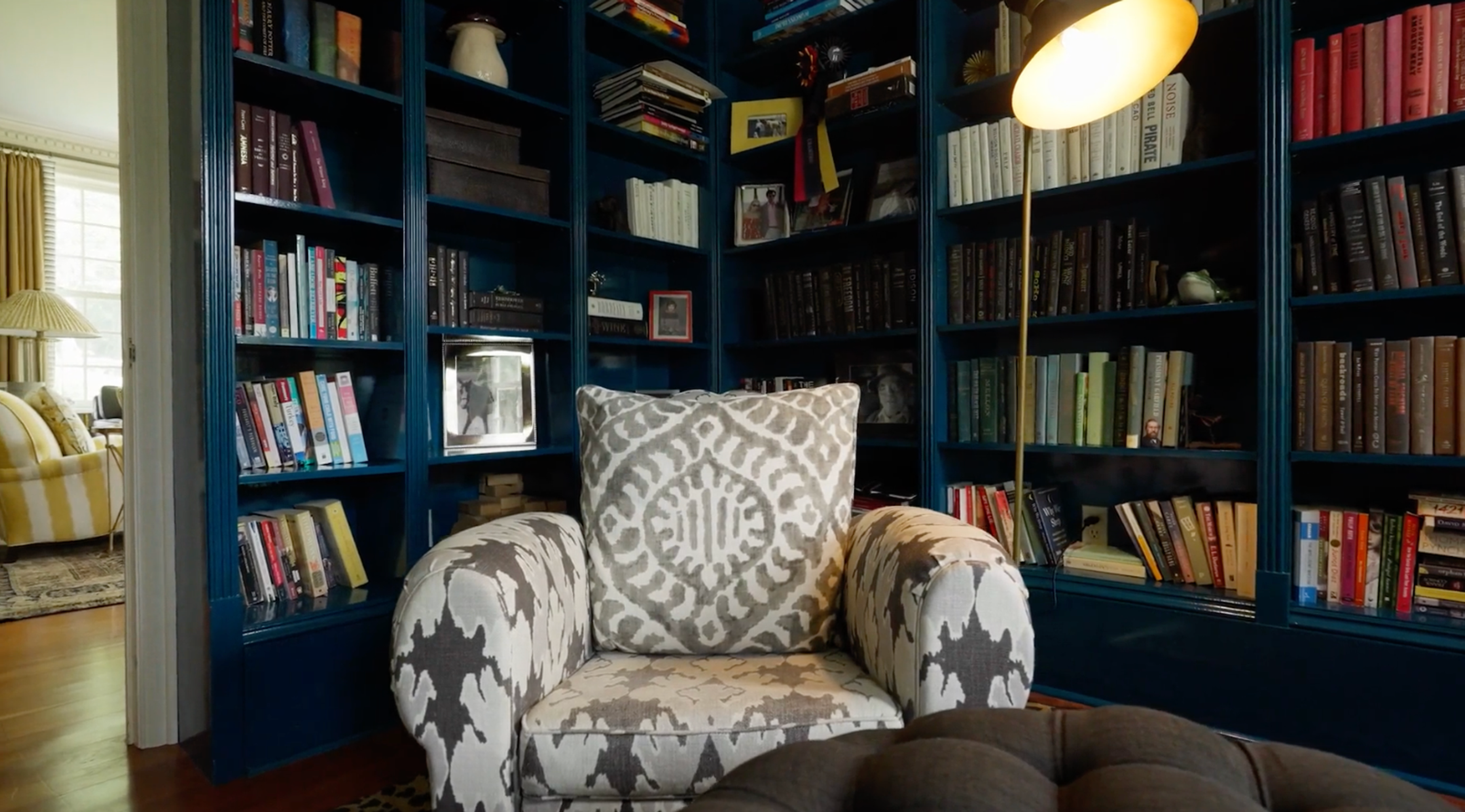 A cozy reading nook with floor-to-ceiling bookshelves and a colorful armchair.