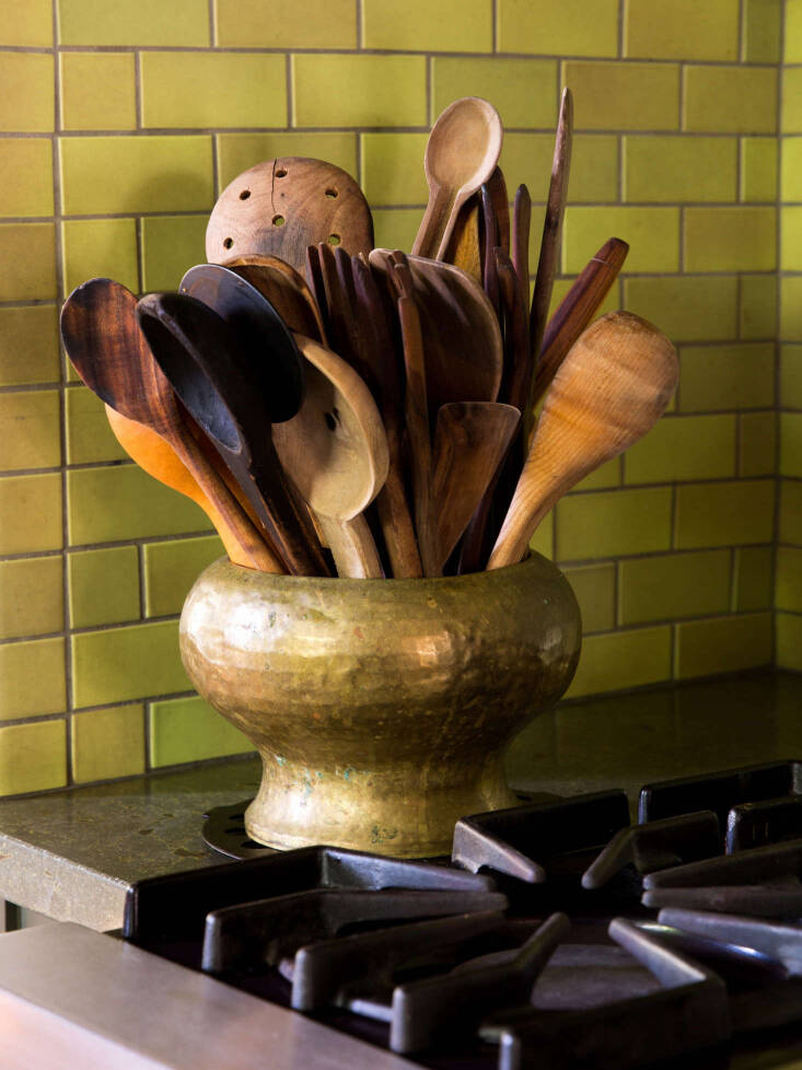 Wooden and metal spoons organized into separate cylindrical containers in Alice Waters' kitchen.