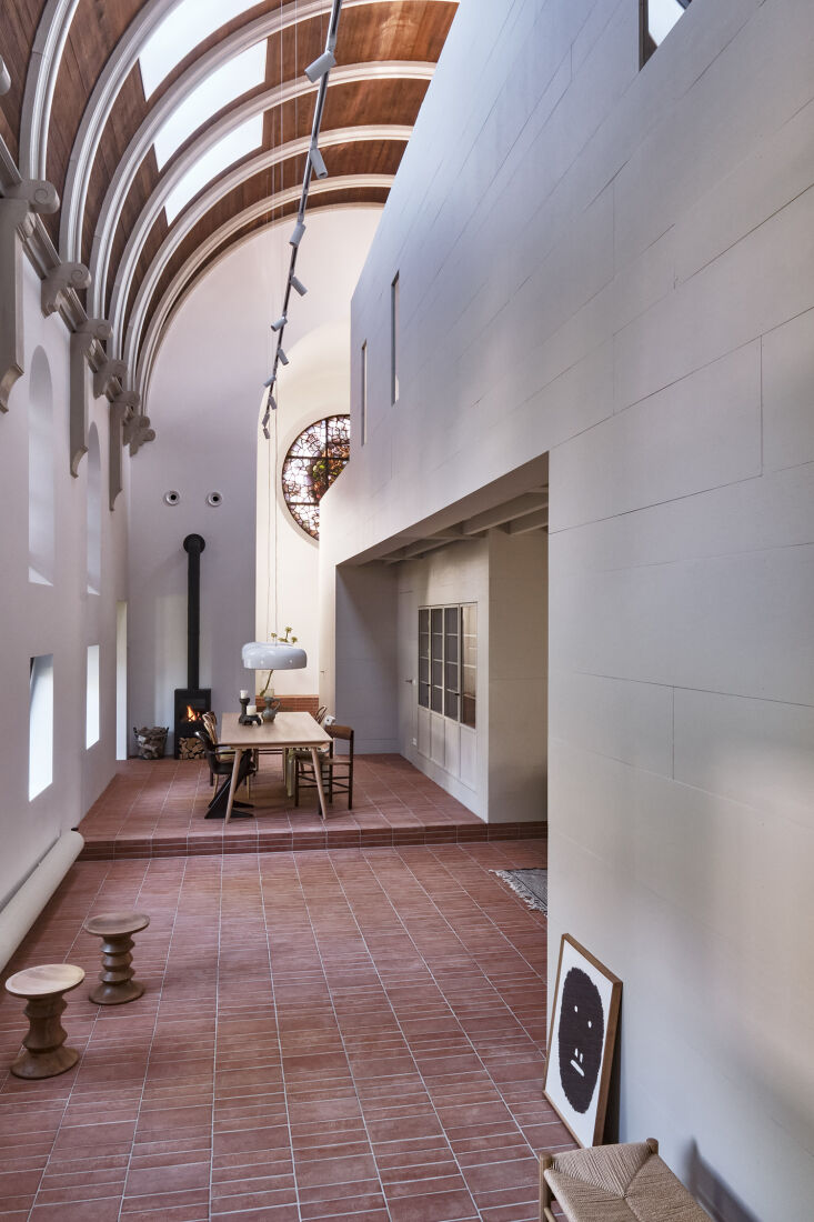 Sunlight streaming through square skylights in an arched ceiling onto terracotta floors.