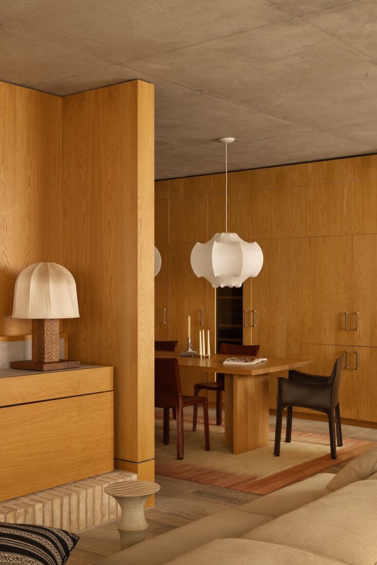 Dining room with a long wood table, leather chairs, and a large sculptural Flos Viscontea pendant light.