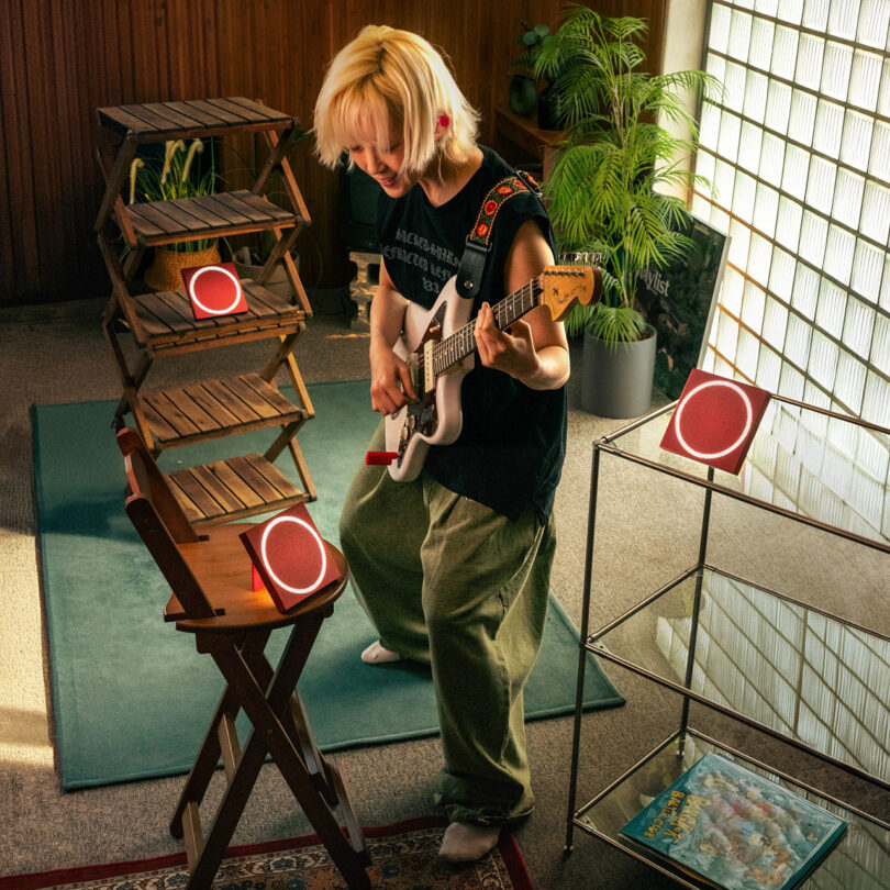 Red speakers and musical equipment integrated into a modern room with wooden shelving.