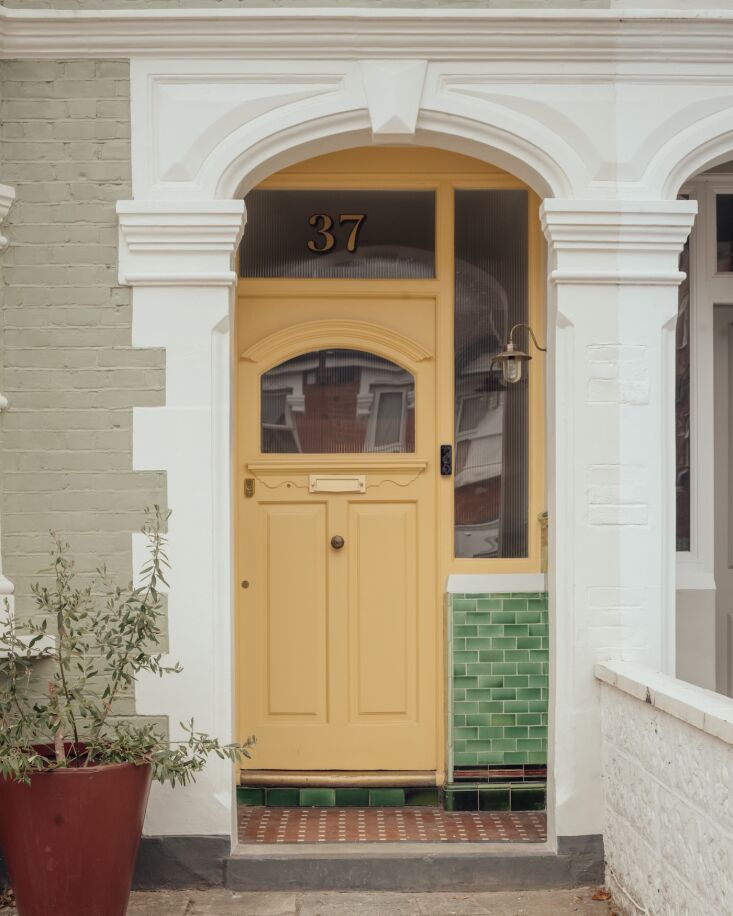 Close-up of a restored Edwardian front door with glazed tiles and green linseed oil paint finish.