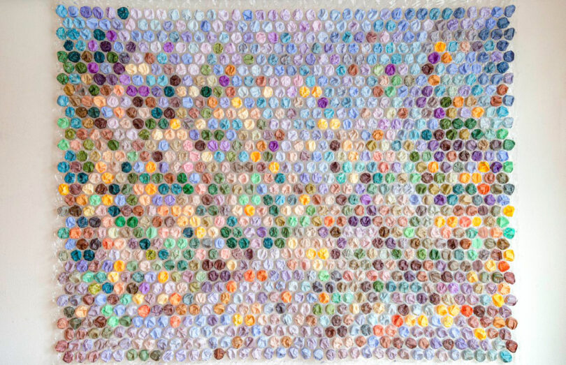 A large wall display featuring hundreds of small, multicolored circles arranged in a precise grid.