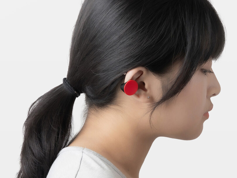 A close-up of a person wearing a large, circular red haptic earpiece.